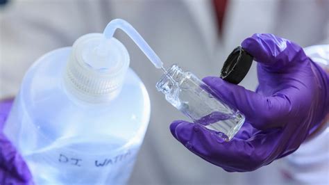 Técnico de laboratorio utilizando agua destilada en un matraz