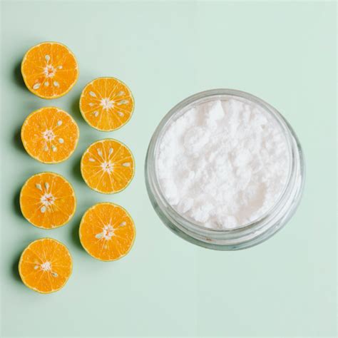 Botella de vitamina C en polvo junto a un recipiente con agua