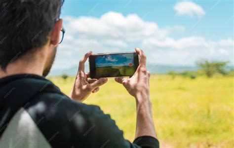 Persona tomando una foto de un paisaje montañoso al amanecer.