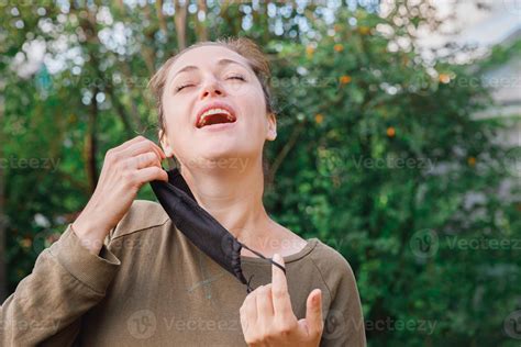 Persona sonriente quitándose una mascarilla al aire libre