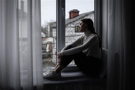 Mujer embarazada con expresión de preocupación mirando por la ventana
