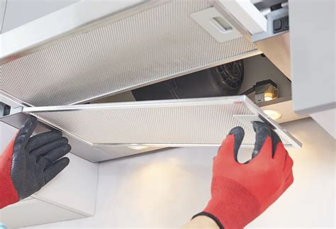 Persona limpiando filtro de campana extractora con desengrasante