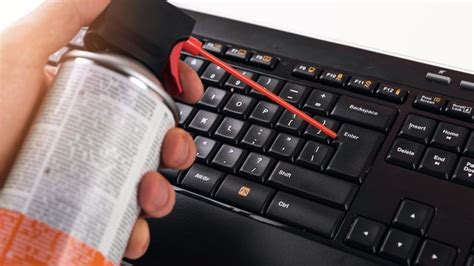 teclado de laptop siendo limpiado con aire