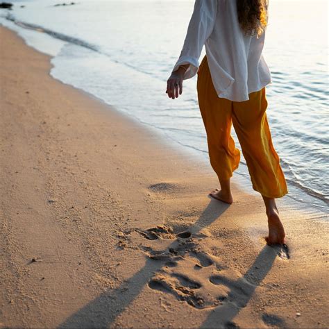 Persona caminando por la playa sintiendo la brisa marina