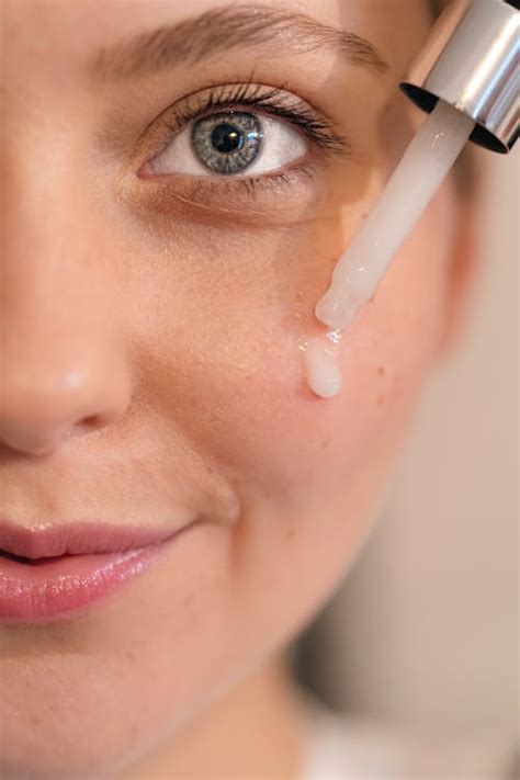 Primer plano de una mujer aplicándose una mascarilla facial cremosa