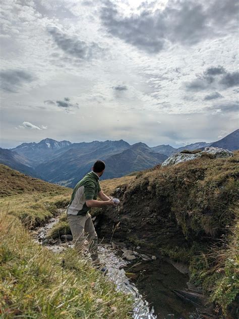 Persona recogiendo agua de un arroyo en la montaña
