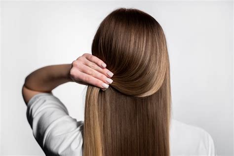 Mujer sonriendo mientras se peina el cabello suave y brillante